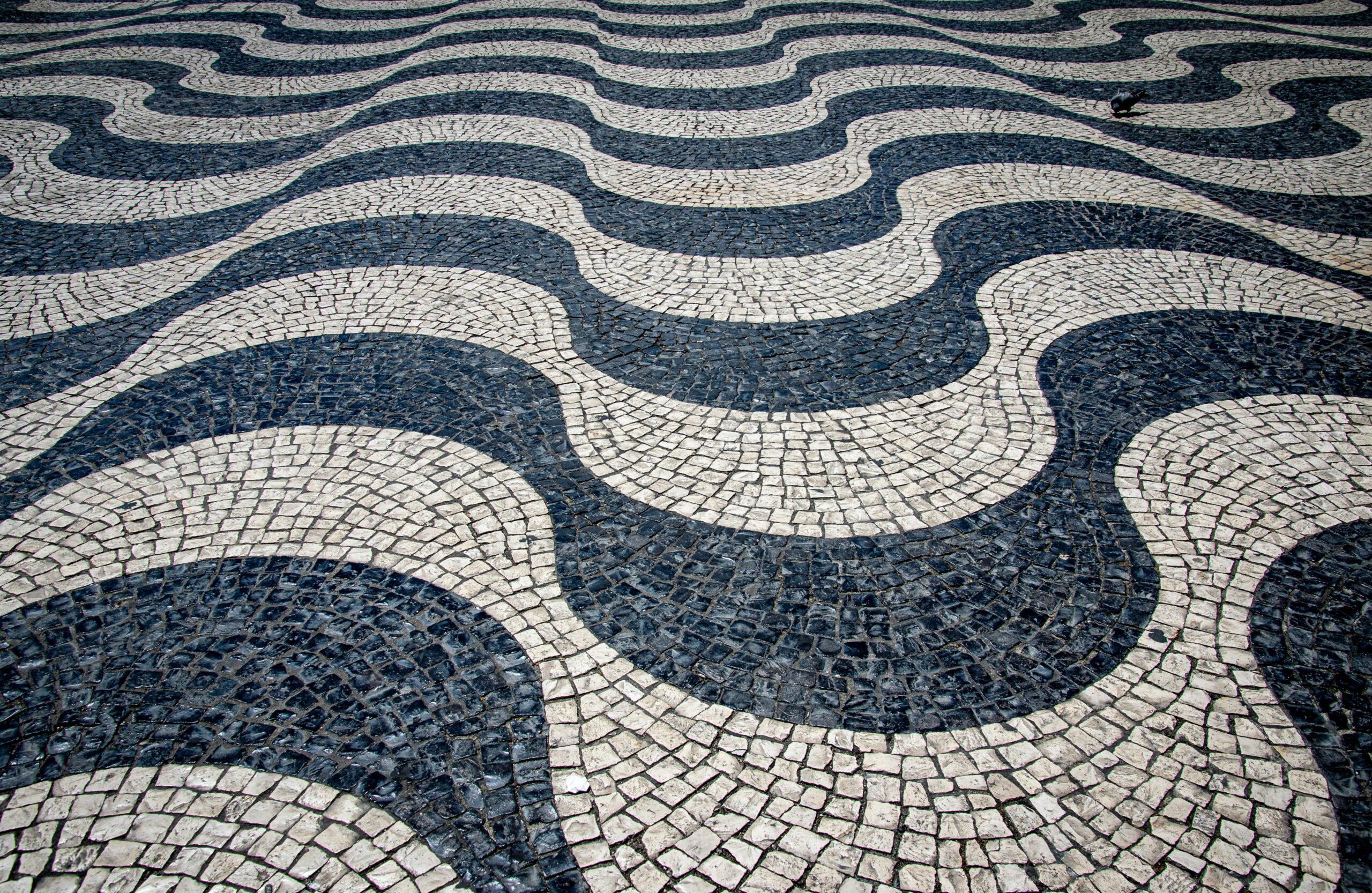 Capture of Lisbon's famous wavy mosaic pavement design in a sunny outdoor setting.